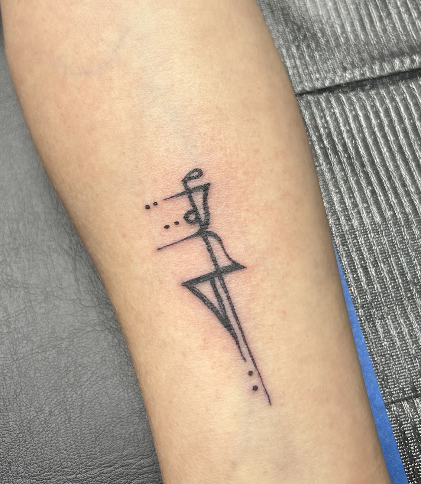 Abstract calligraphic symbol in black ink on a forearm