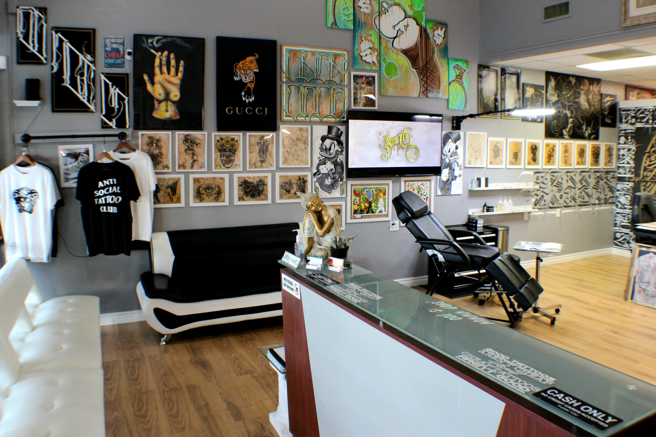 Front room of the shop: black and white leather seating, walls covered in framed art, and a gold Buddha on the glass counter